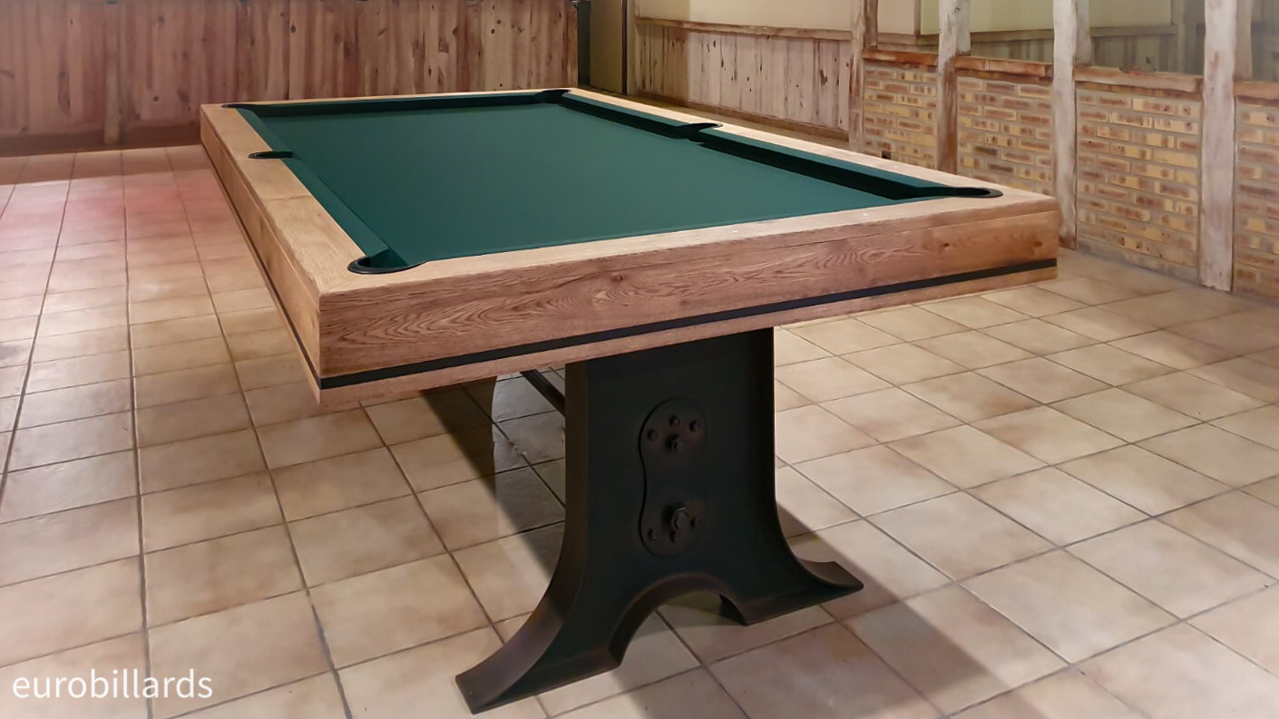 Avec ses deux magnifiques pieds tulipes en métal couleur rouille soutenant le cadre de jeu en chêne finition brossé huilé, habillé d'un tissu vert épicéa, le billard ATELIER appartient clairement à la lignée des meubles de style industriel qui prends légitimement sa place au sein de cette salle aux murets de pierres et poutres en bois nature.